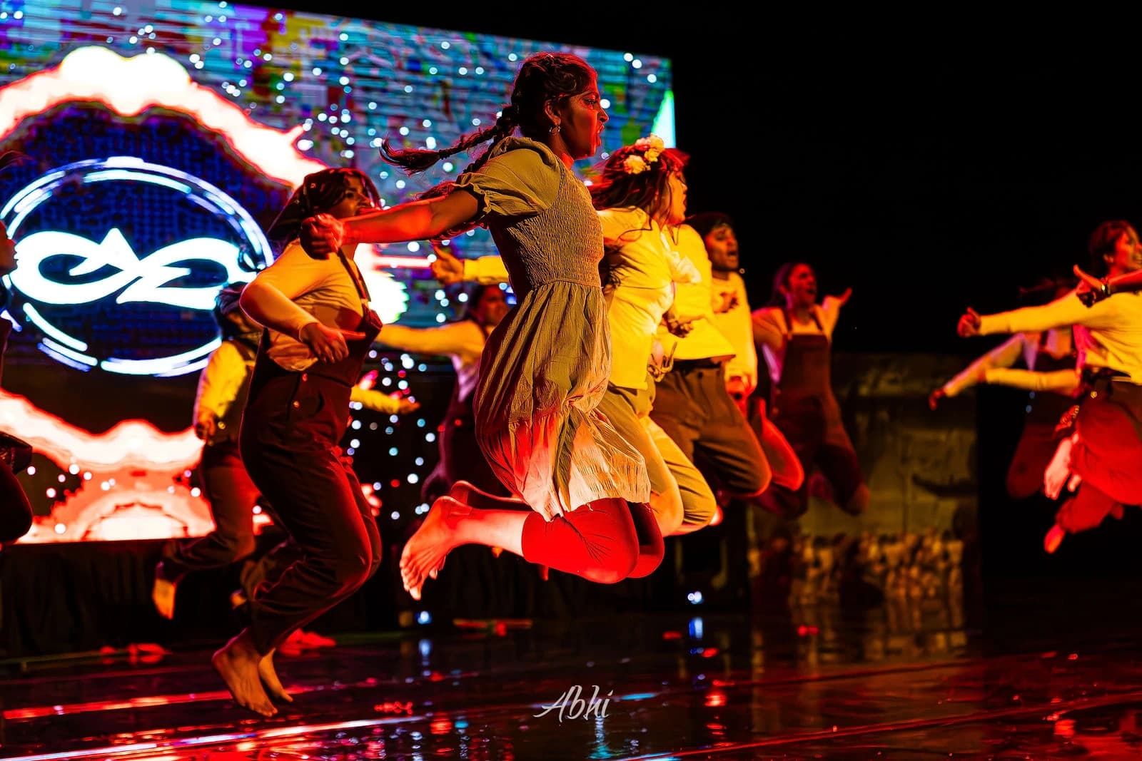 NDDL dancers leaping together in front of a vivid stage backdrop